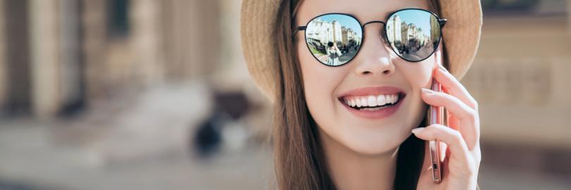 Frau mit Hut und Sonnenbrille telefoniert mit Handy