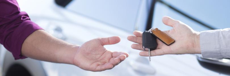 In der Nahaufnahme von zwei Händen übergibt ein Mann einer Frau einen Autoschlüssel