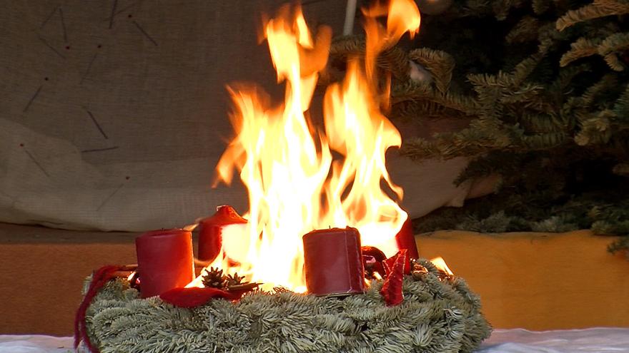 Flammen schlagen aus der Mitte eines Adventskranzes in die Höhe.