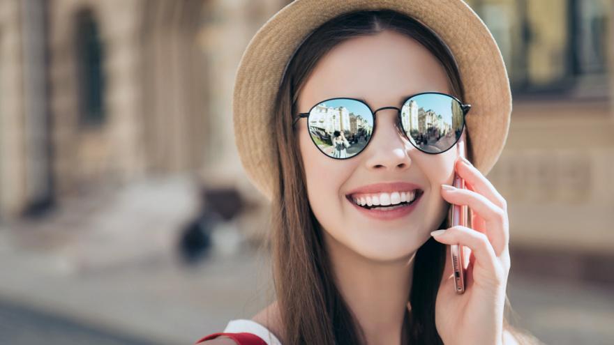 Frau mit Hut und Sonnenbrille telefoniert mit Handy