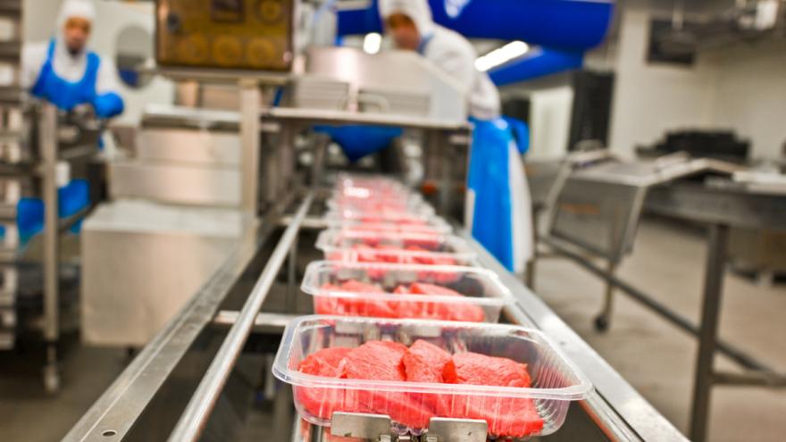 Maschinelle Herstellung von Fleisch: Im Vordergrund läuft ein Fließband mit fertigen Packungen.