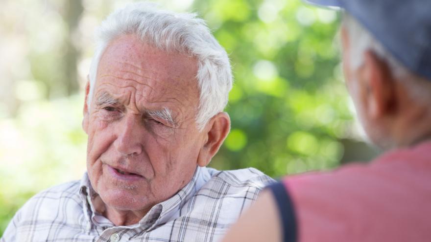 Ein unzufrieden schauender Senior sitzt im Garten