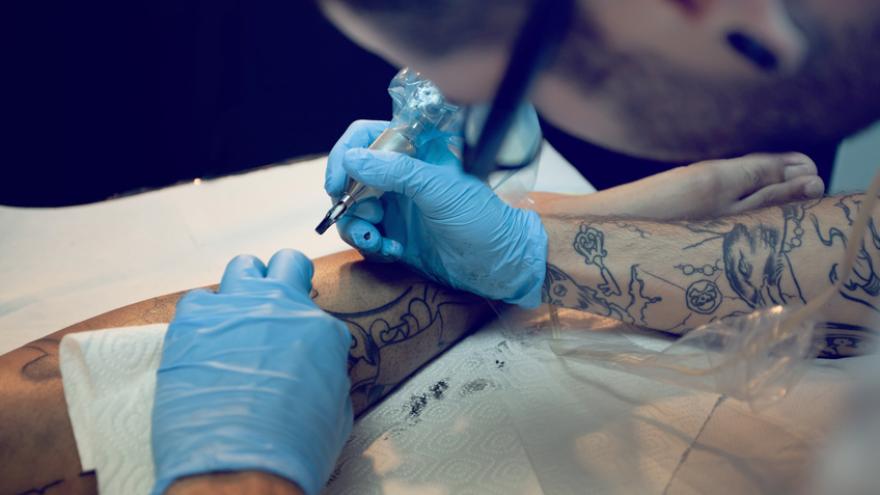 Ein Tätowierer sticht einem Kunden ein Tattoo