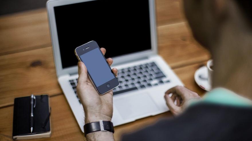 Telefon Handy Mann am Laptop mit Handy