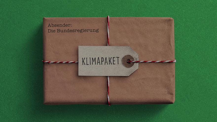 ein braunes Paket liegt auf einem grünen Tisch, darauf steht "Klimapaket"