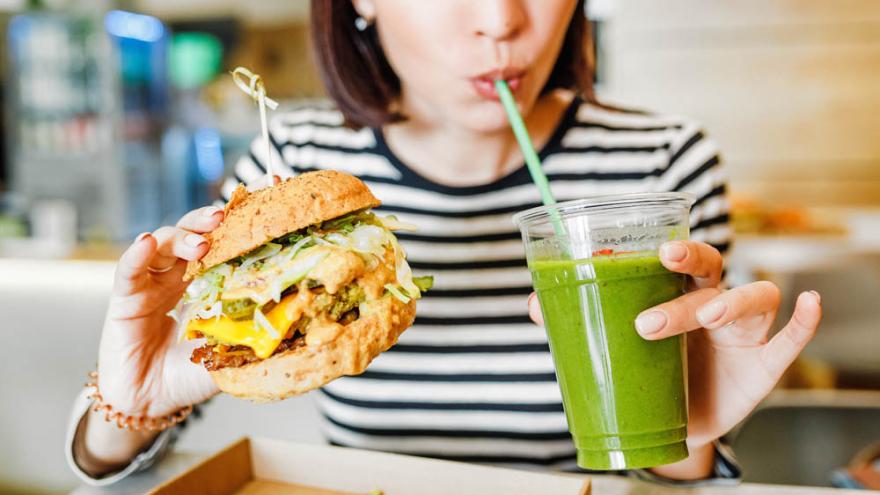 Frau mit veganem Burger und Smoothie