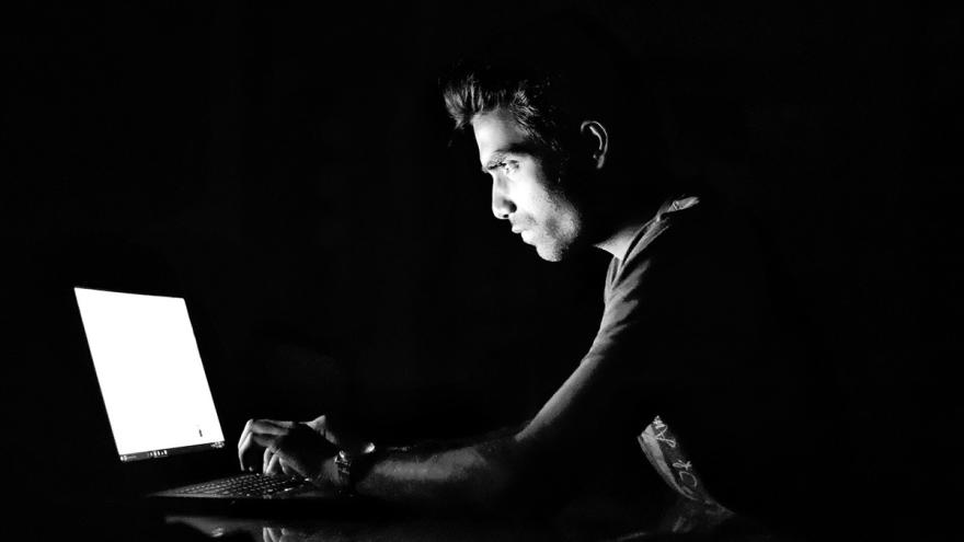 Düstere Schwarz-Weiß-Aufnahme eines Mannes, der vor einem Laptop sitzt