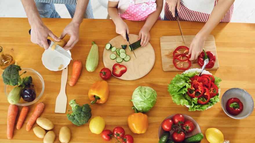 Drei Personen schneiden Gemüse und bereiten Essen vor