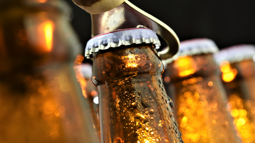 Bierflaschen, deren Verschluss mit einem Bieröffner geöffnet wird, dunkler Hintergrund