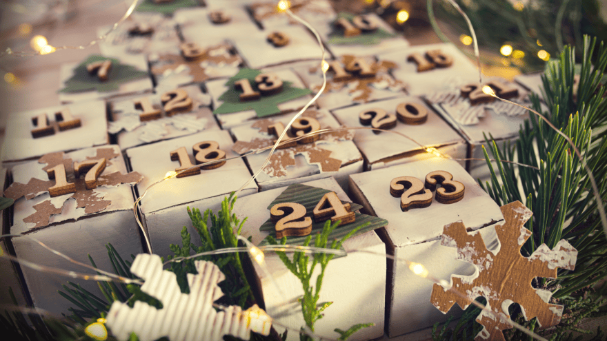 Weiße Würfel mit hölzernen Zahlen als Adventskalender in Tannenbaumform zusammengesetzt.