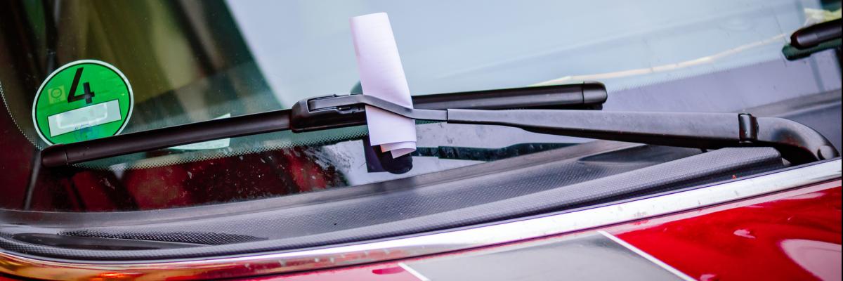 Hinter einem Scheibenwischer klemmt ein Knöllchen am Auto