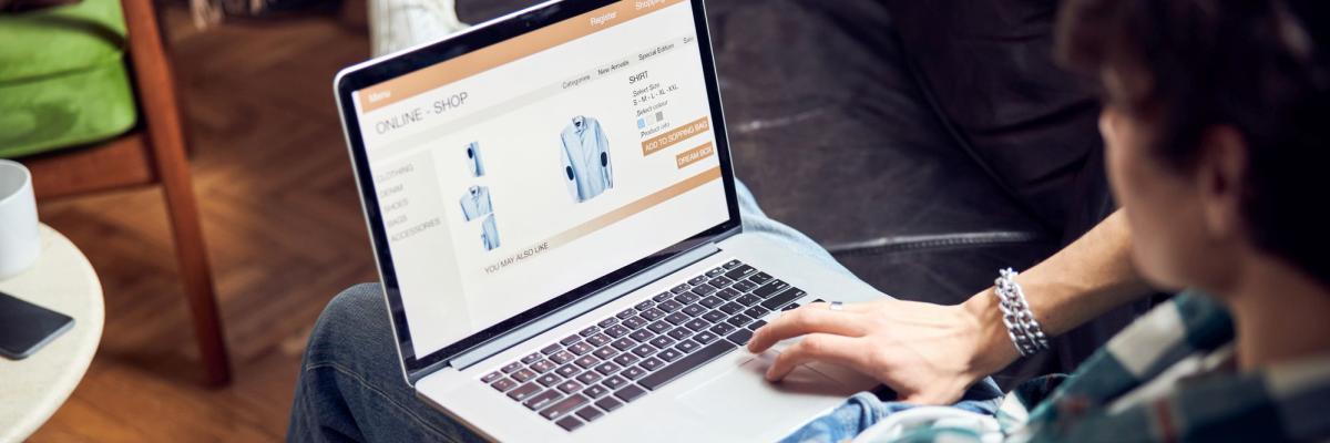 Eine Person mit Laptop auf dem Schoß, auf dem Bildschirm ist eine Online-Shop zu sehen.