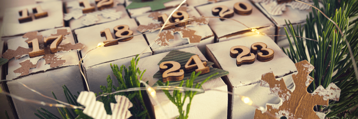 Weiße Würfel mit hölzernen Zahlen als Adventskalender in Tannenbaumform zusammengesetzt.