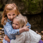 Zwei kleine Mädchen umarmen sich im Wald