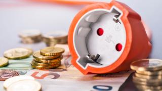 Steckdosen liegen auf Geldscheinen und Geldmünzen