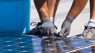 Person installiert Photovoltaikanlage