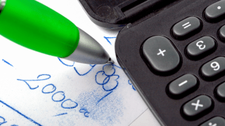 Taschenrechner, Stift und ein Zettel mit einer Rechnung