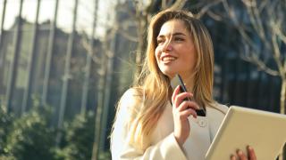 Junge Frau mit Smartphone und Tablet in der Hand schaut nach rechts